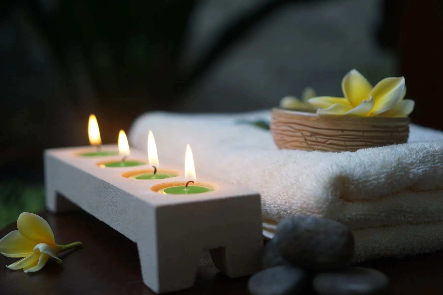 Bougies allumées, serviettes roulées et fleur de frangipanier
